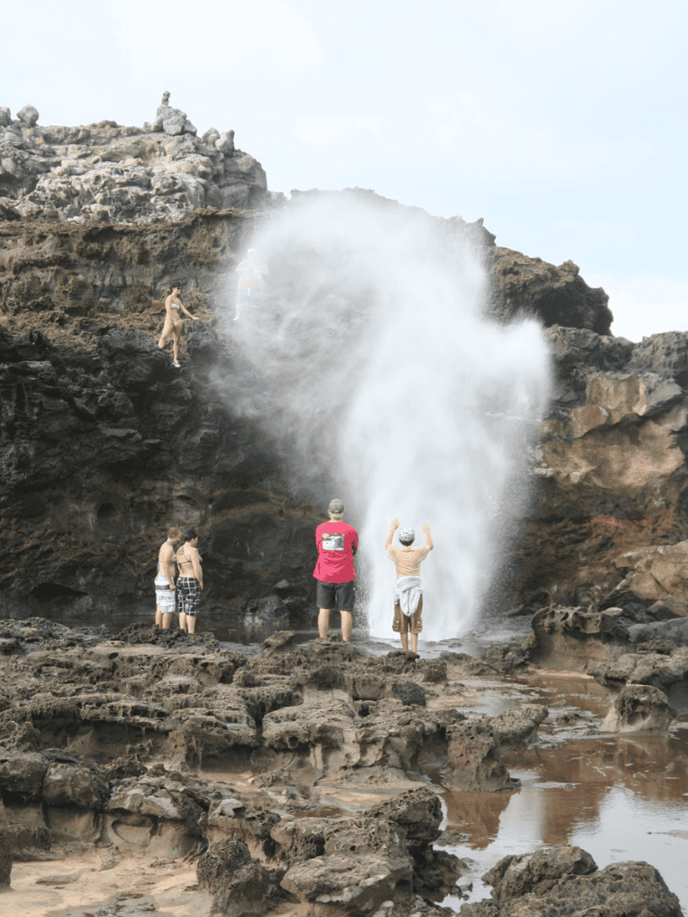 Active family exploring ocean rocks and waterfall adventure.