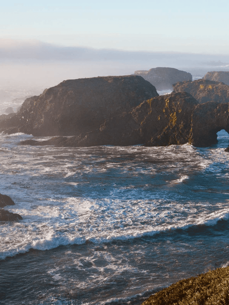 Rocky coastline with waves crashing and a scenic ocean view.