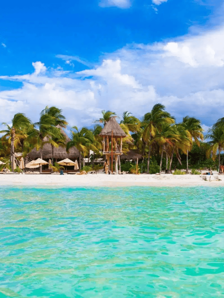 Pristine tropical beach with palm trees, thatched huts, and turquoise water, perfect for vacation.