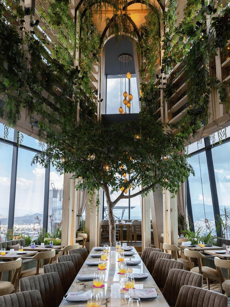 Lush indoor restaurant with large windows, greenery, and mountain views at QuestForDirections.