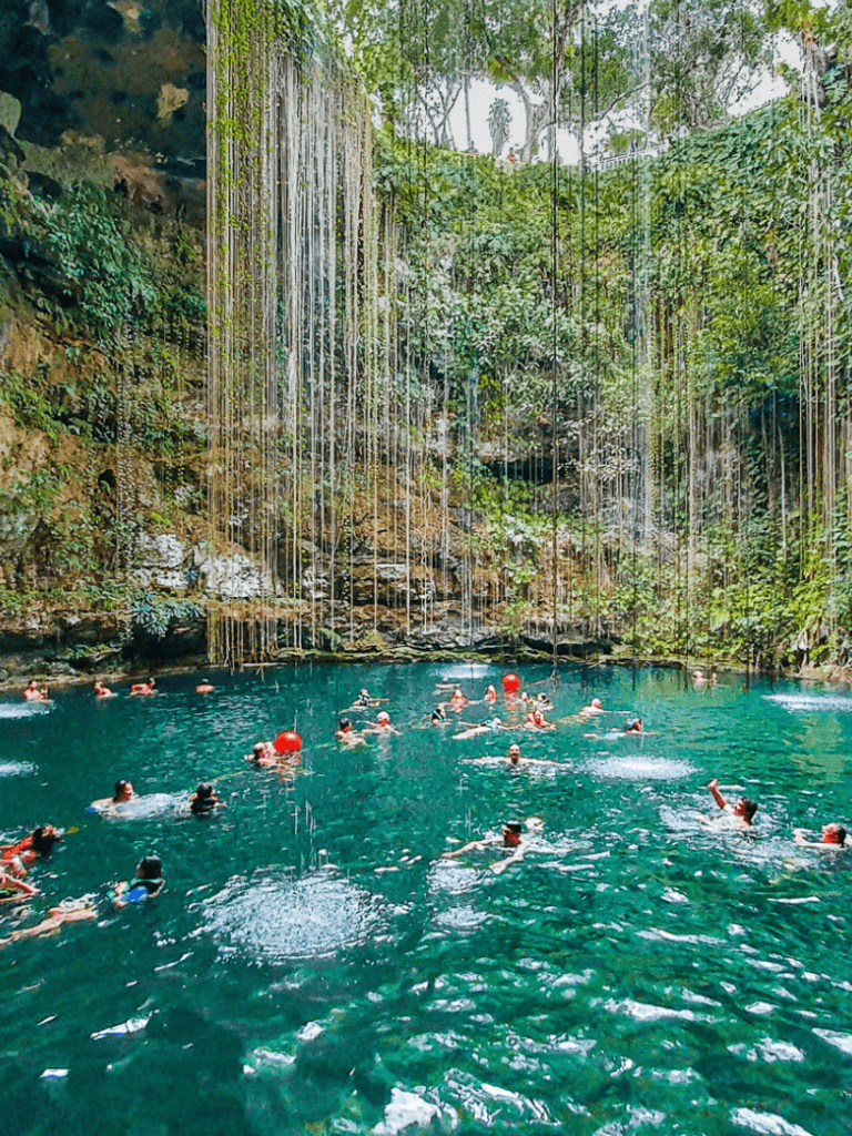 Brightly colored swimming spot with waterfall in lush jungle setting, popular for adventure and nature lovers.