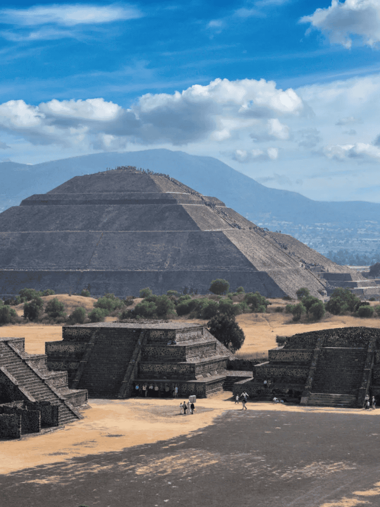Ancient Mesoamerican pyramid at Teotihuacan, Mexico, with modern visitors exploring the archaeological site.