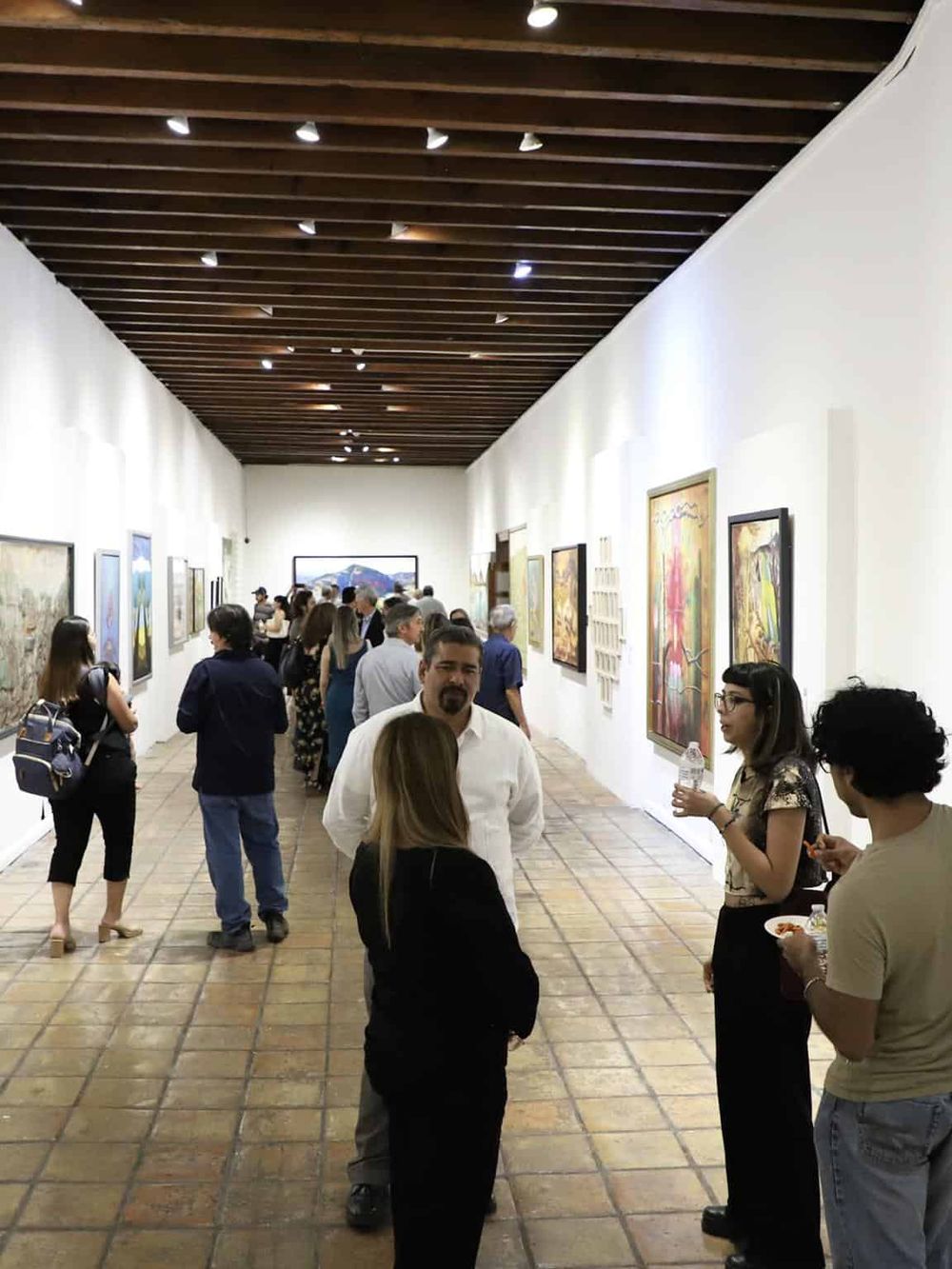 Vibrant art gallery with diverse visitors viewing contemporary paintings and sculptures, embodying a cultural art experience.