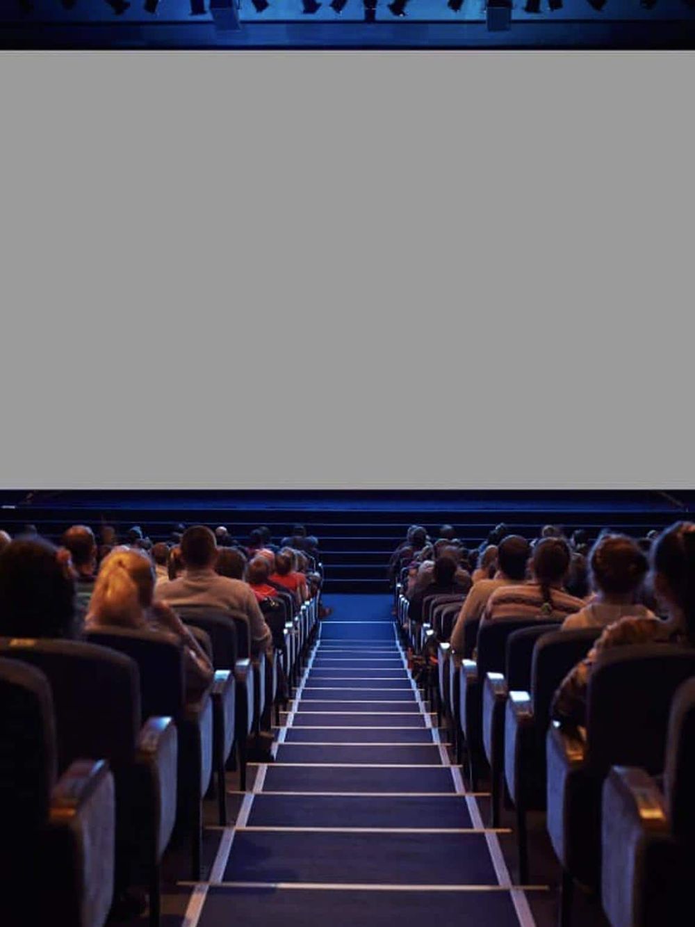 People watching a movie at a modern cinema theater with large projection screen and comfortable seats.
