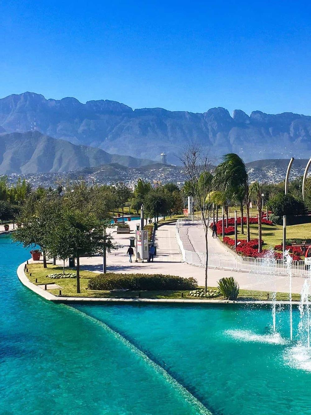 Vibrant park with walking paths, water features, and mountain views in QuestForDirections city.