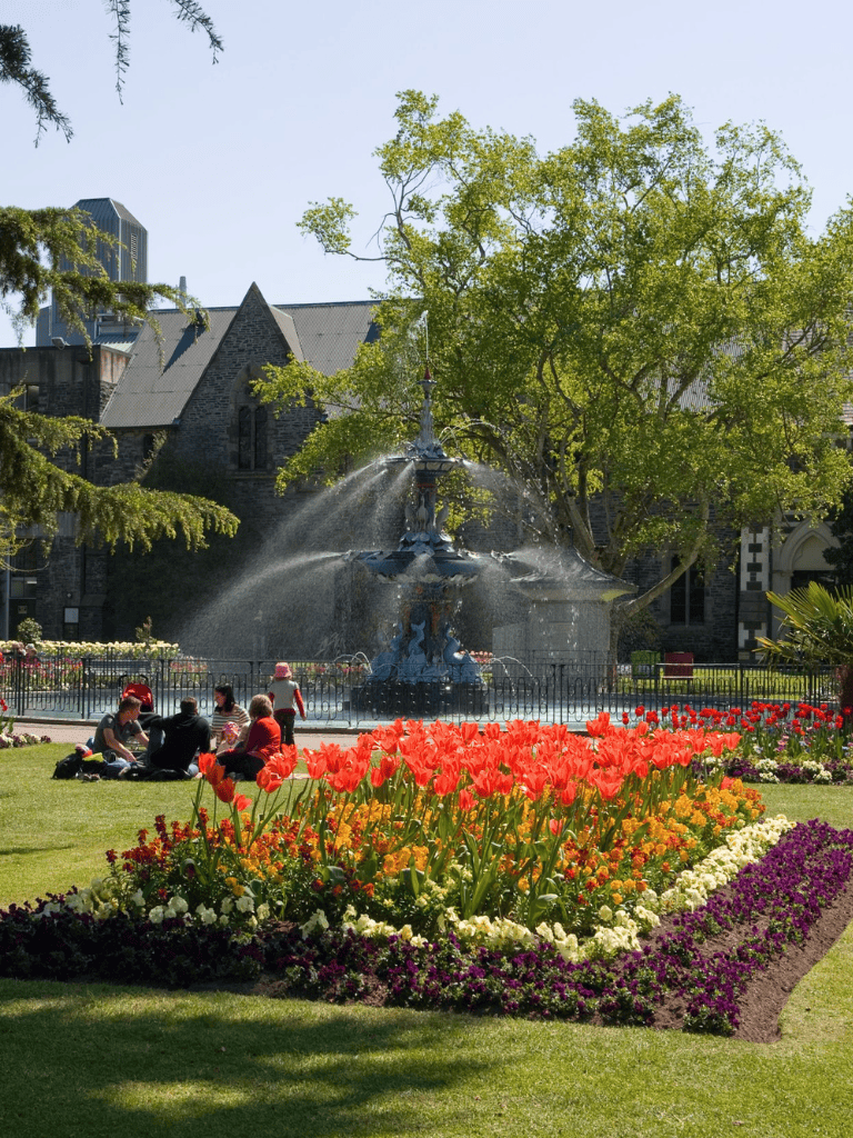 Colorful flower garden with fountain and historic building in the background, beautiful outdoor scenery in downtown.