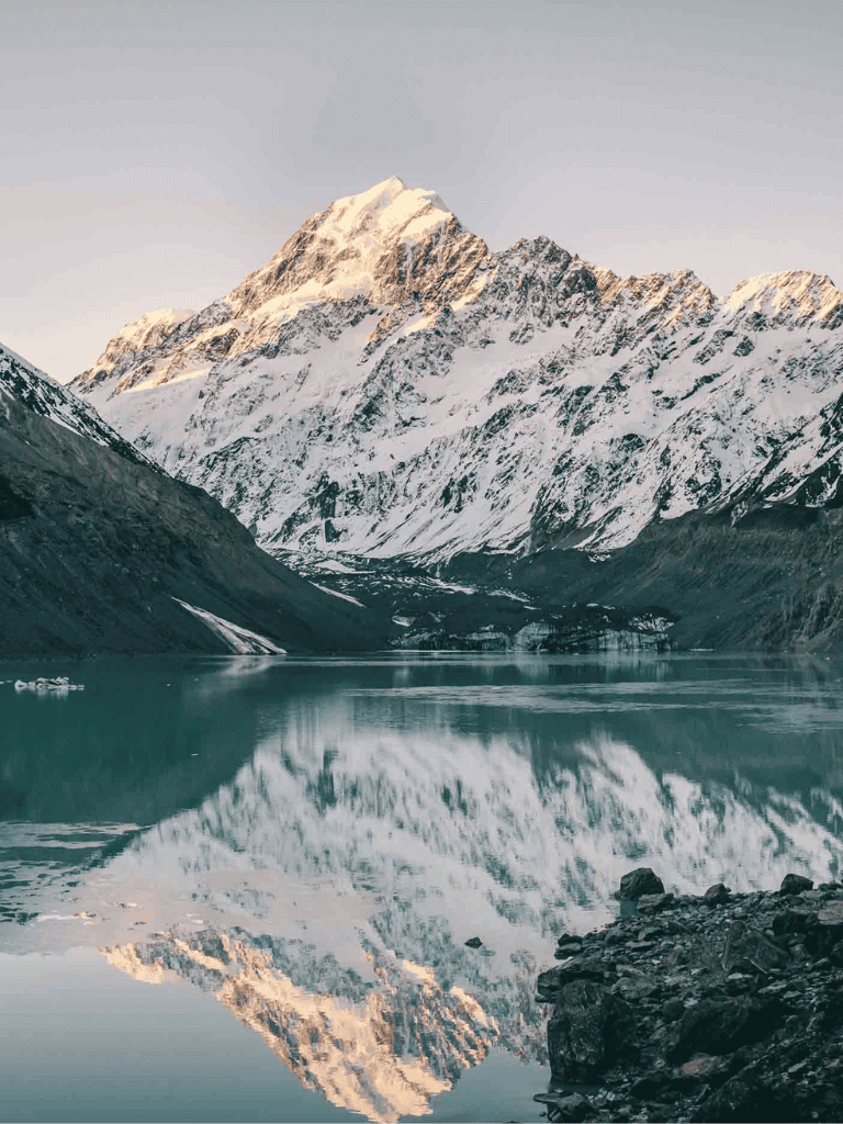 Serene snow-capped mountain landscape with reflective lake in New Zealand.