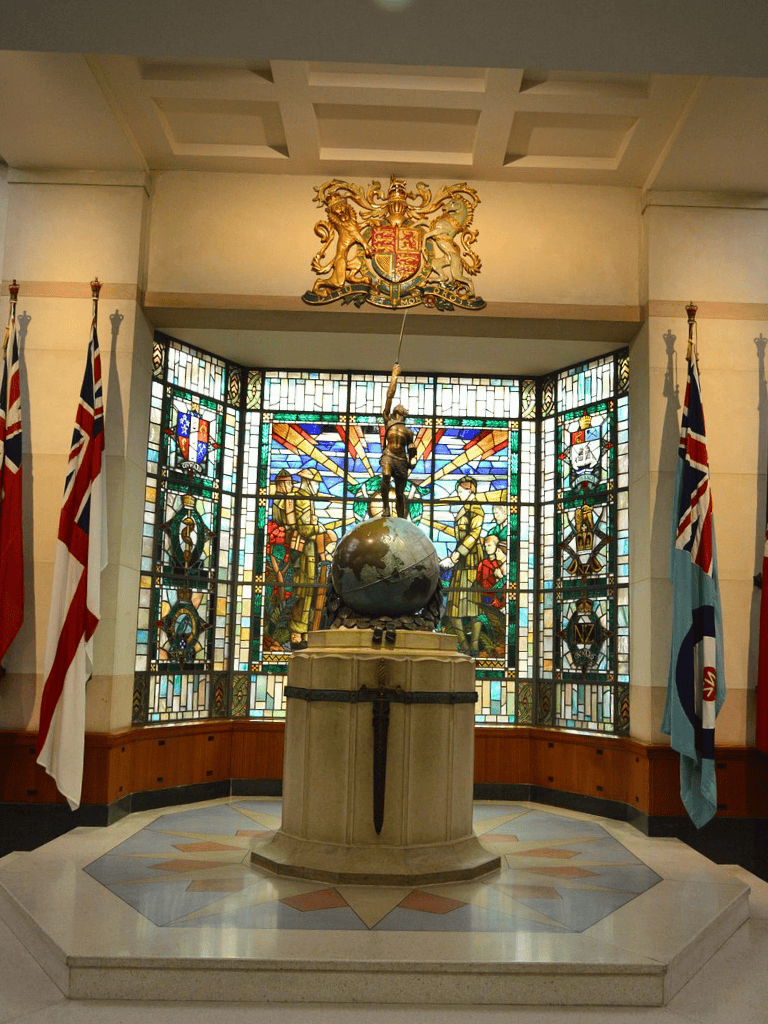 Britannia statue and stained glass window in UK government building interior.
