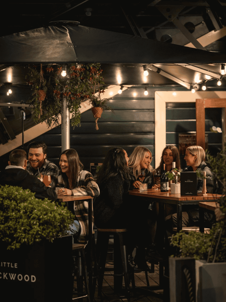 Cozy outdoor dining at QuestForDirections with friends enjoying drinks under string lights.