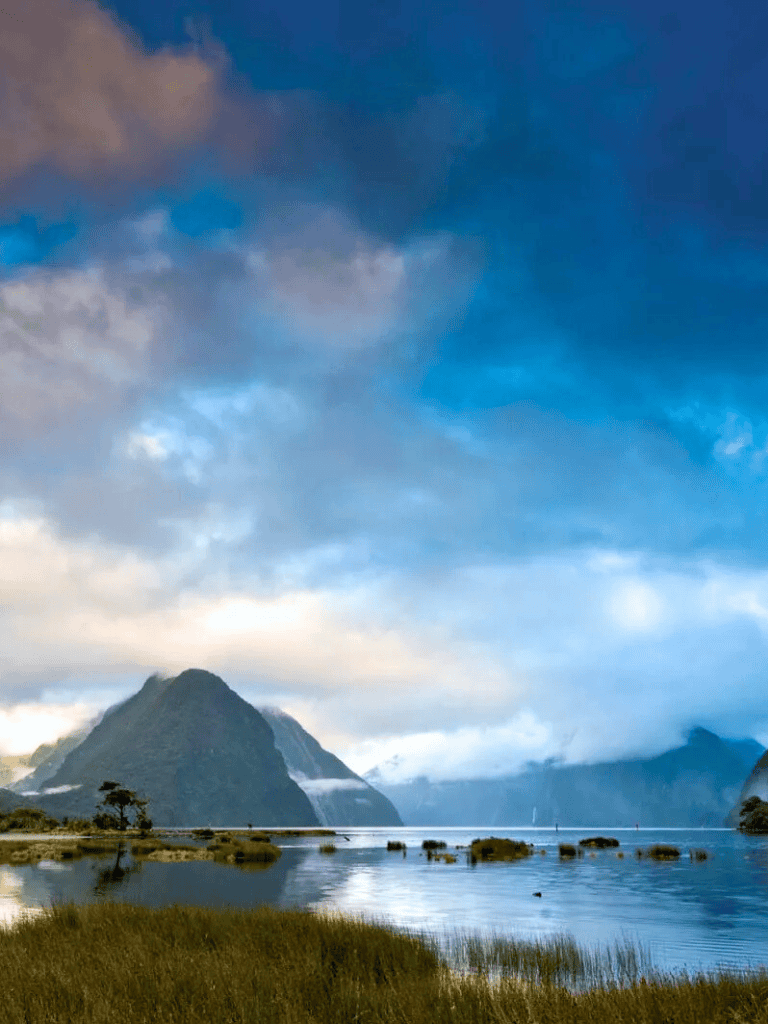 Serene mountain lake with lush greenery and dramatic sky, perfect for nature and adventure travel.