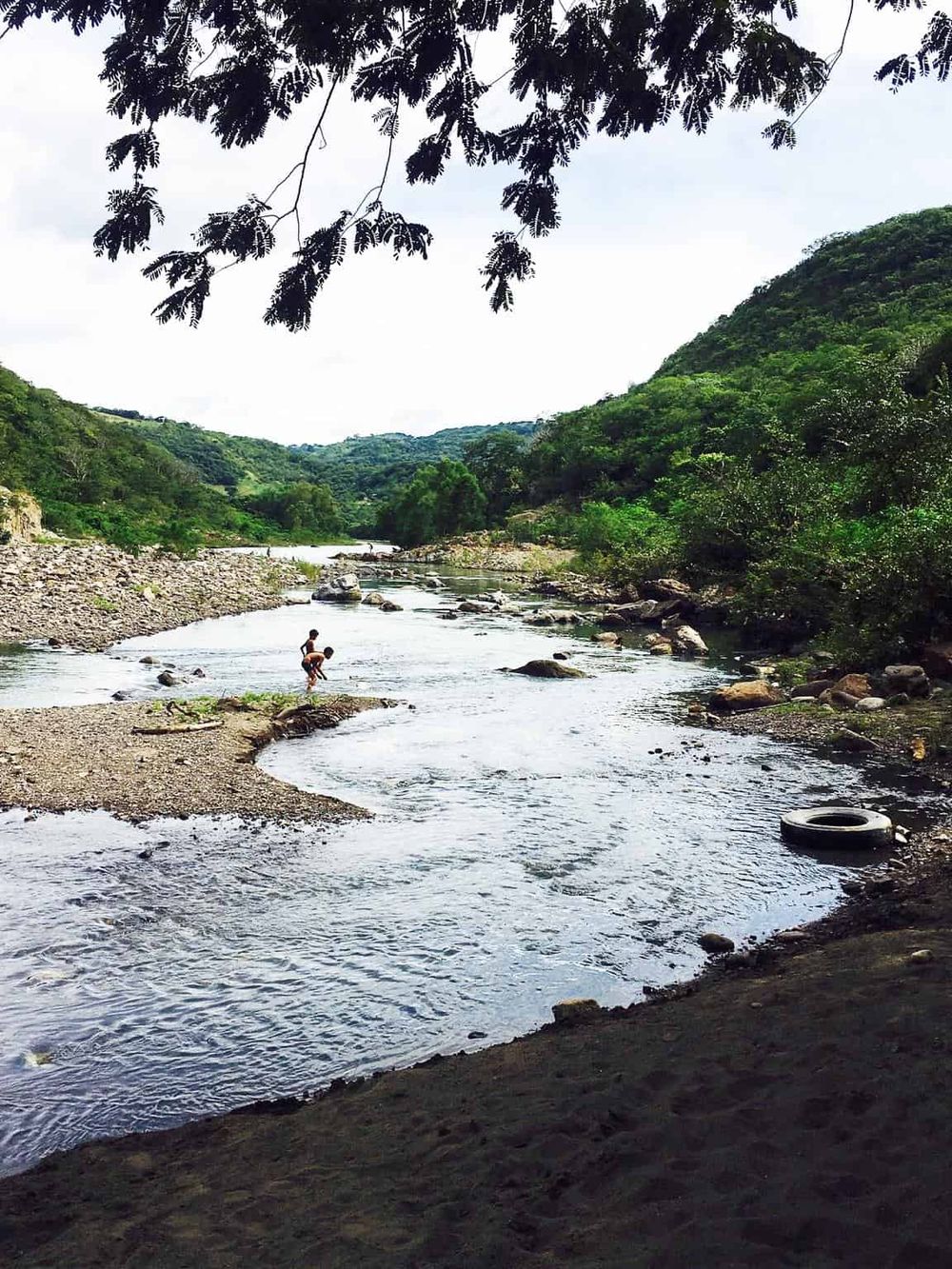 Kids playing in river, outdoor adventure, nature exploration, family fun, scenic landscape, QuestForDirections, travel guide, outdoor activity, river recreation, water exploration.