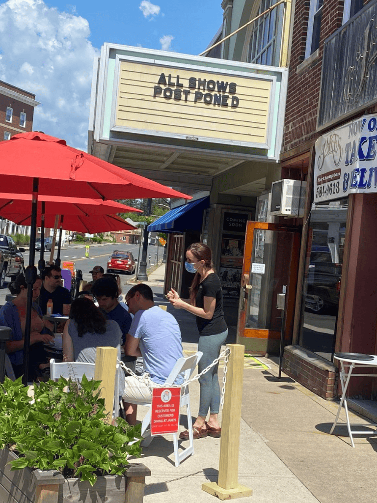 Outdoor dining at Quest for Directions restaurant, with customers and staff wearing masks.