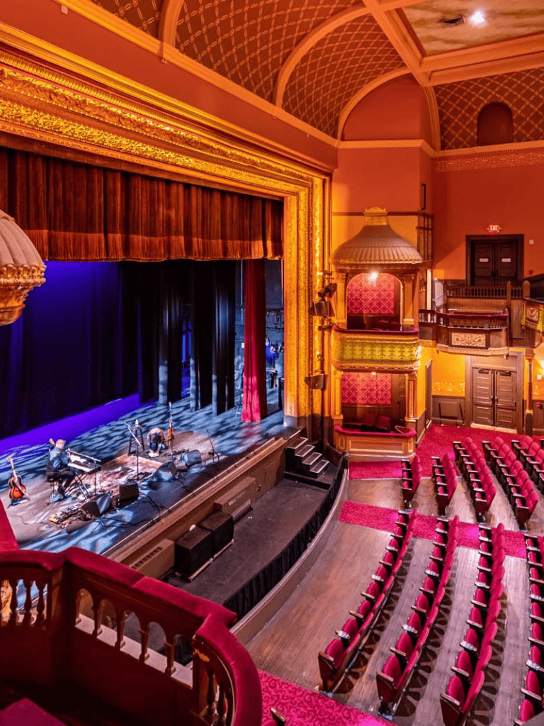 1. Elegant historic theater with ornate gold accents and cozy red seating for live performances.