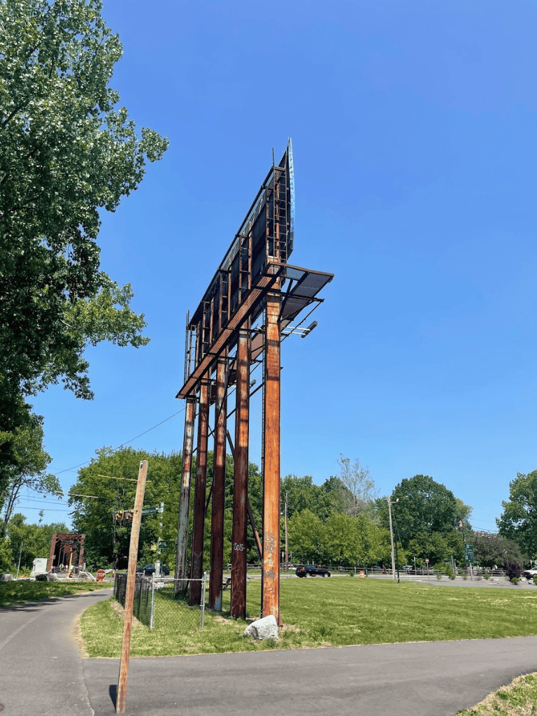 Worn old billboard structure on wooden supports against a clear blue sky.