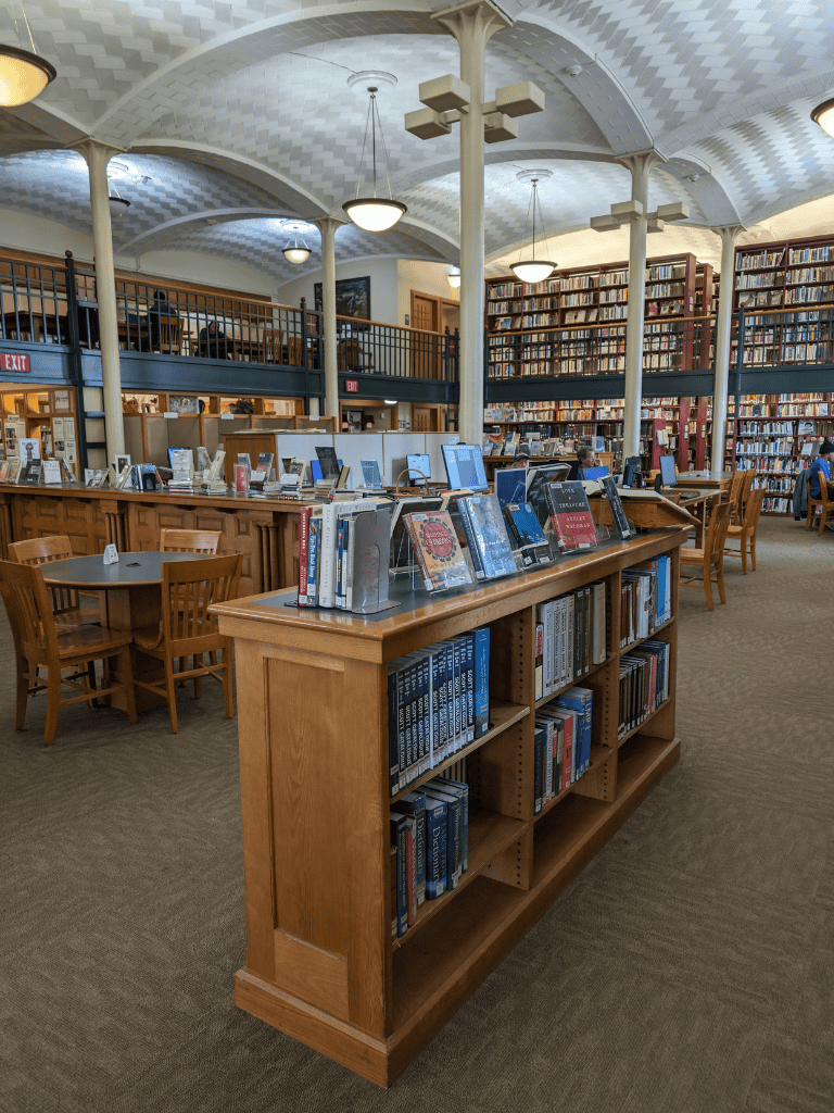 Indoor library scene with wooden bookshelves and tables, cozy reading environment, QuestForDirections.