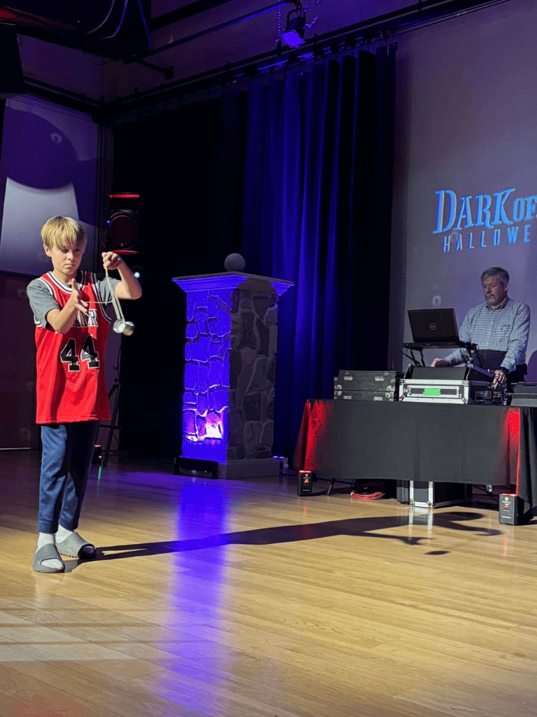 Kid performing magic trick with Yo-Yo at QuestForDirections Halloween event, showcasing entertainment and fun activities.