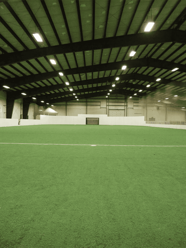 Indoor soccer field with lush green turf and high ceiling at QuestForDirections facility.