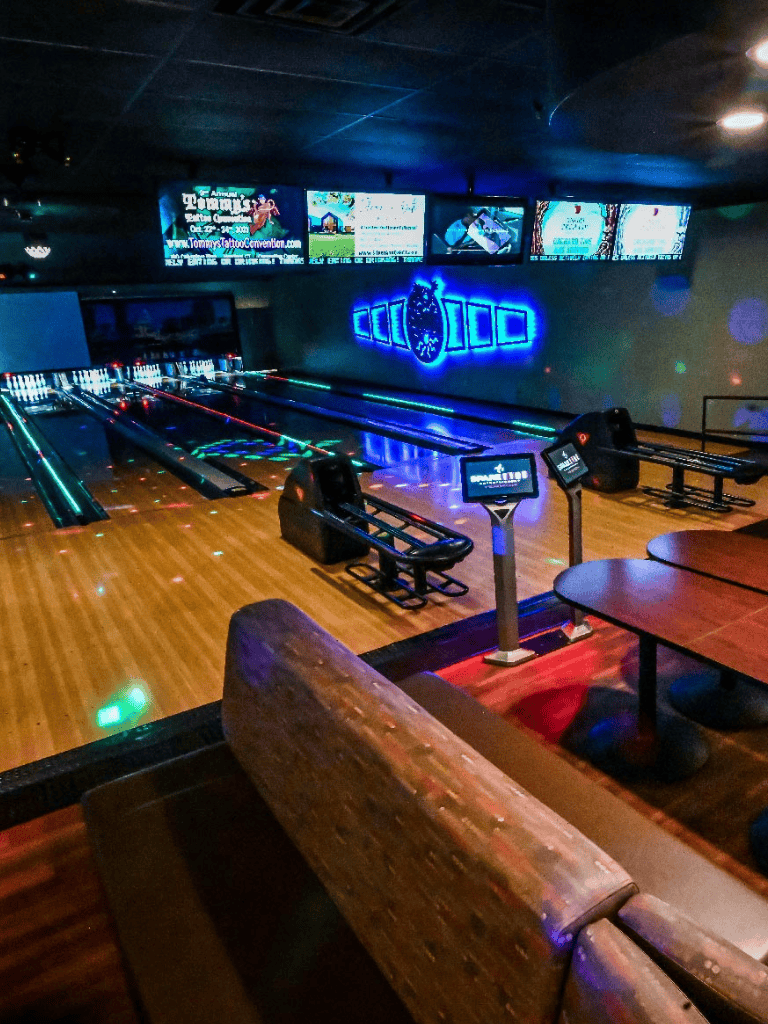 Brightly lit bowling alley with digital scoring screens and neon decorations, showcasing a fun entertainment experience.