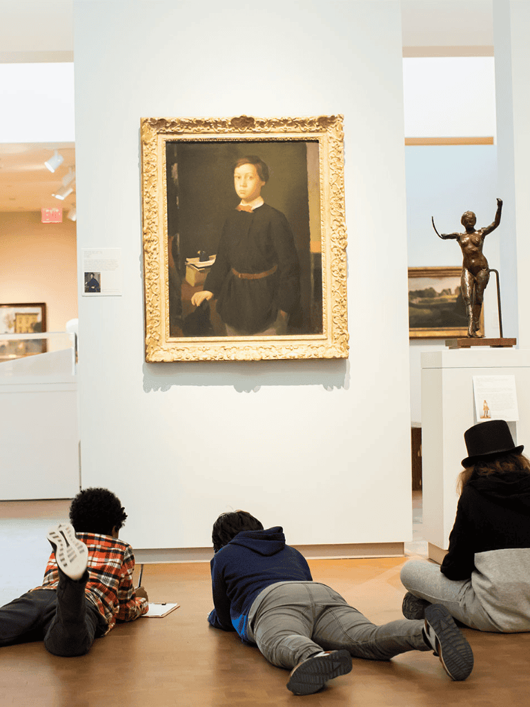 Vibrant art museum with children studying paintings, modern sculptures, and classic artwork on display.