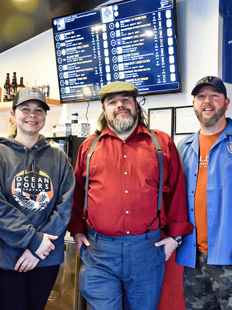 Friendly staff at QuestForDirections restaurant with menu display in background.