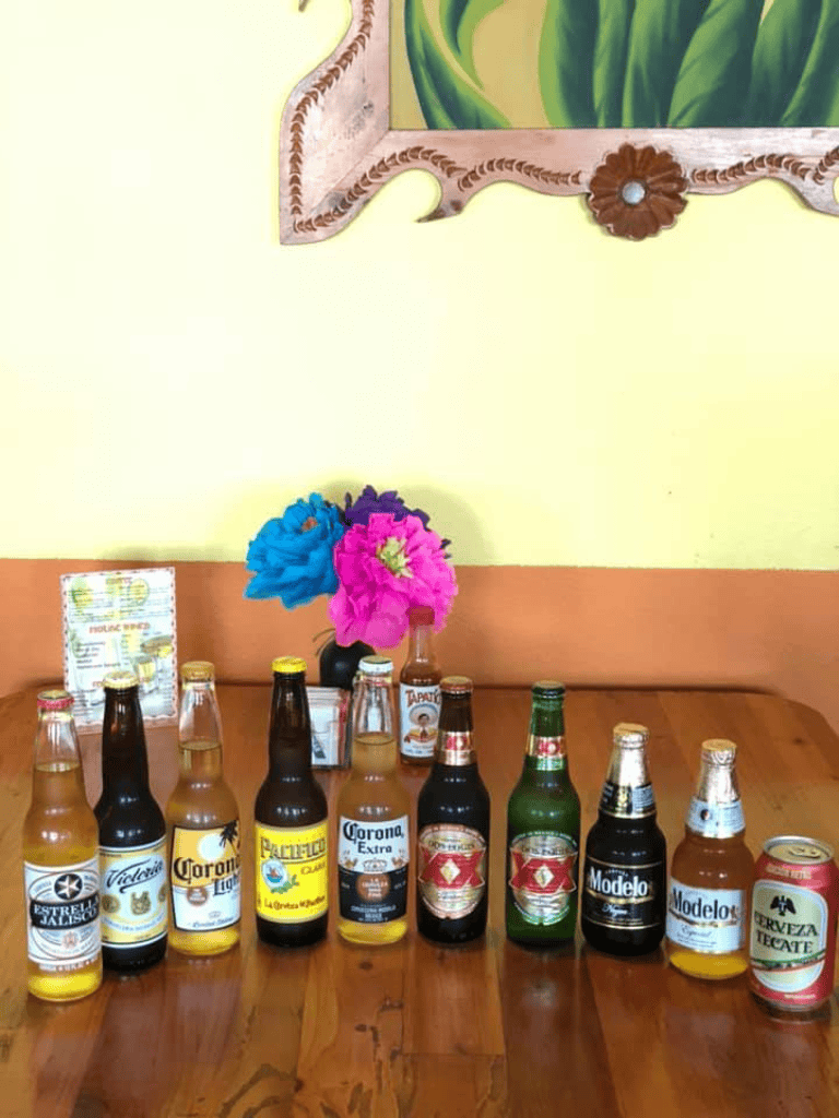 Colorful beer bottles arranged on a wooden table at a Mexican restaurant.