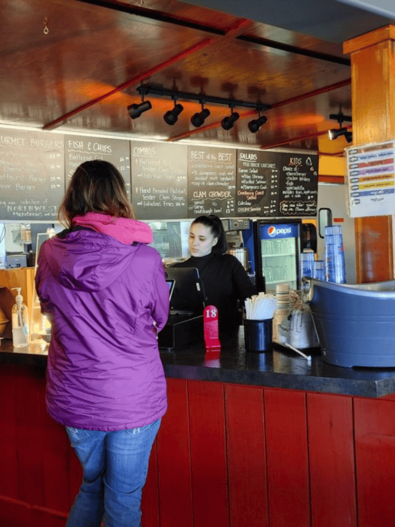 Delicious seafood and burger orders at a cozy restaurant counter with menu boards in the background.