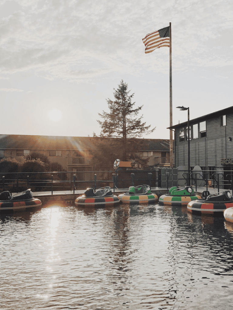 Colorful bumper boats at Quest for Directions amusement park with American flag and sunset view.