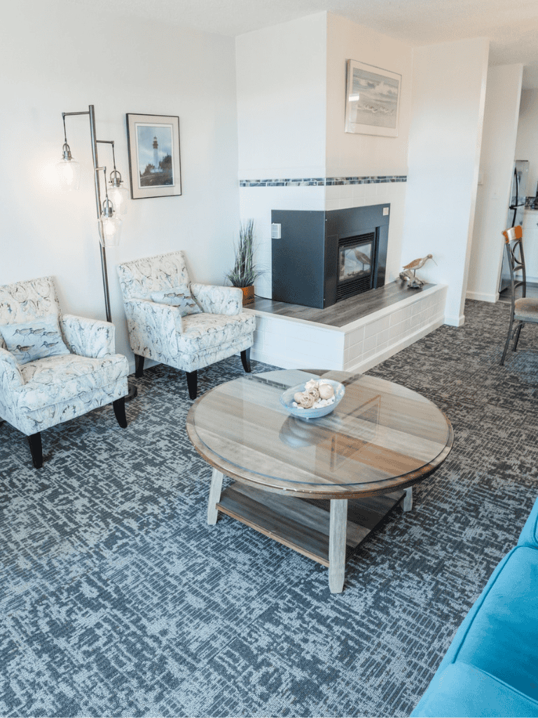 Cozy living room with fireplace and comfortable chairs, ideal for relaxing or entertaining guests.