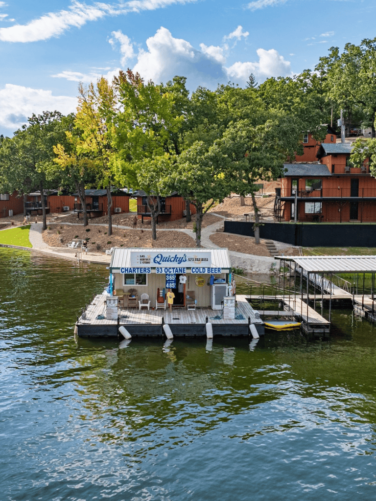 1. Boat rental dock with Quicky's boat rental on the water, near shoreline and trees.