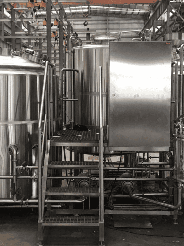 Stainless steel industrial brewing equipment in factory, used for beverage production.