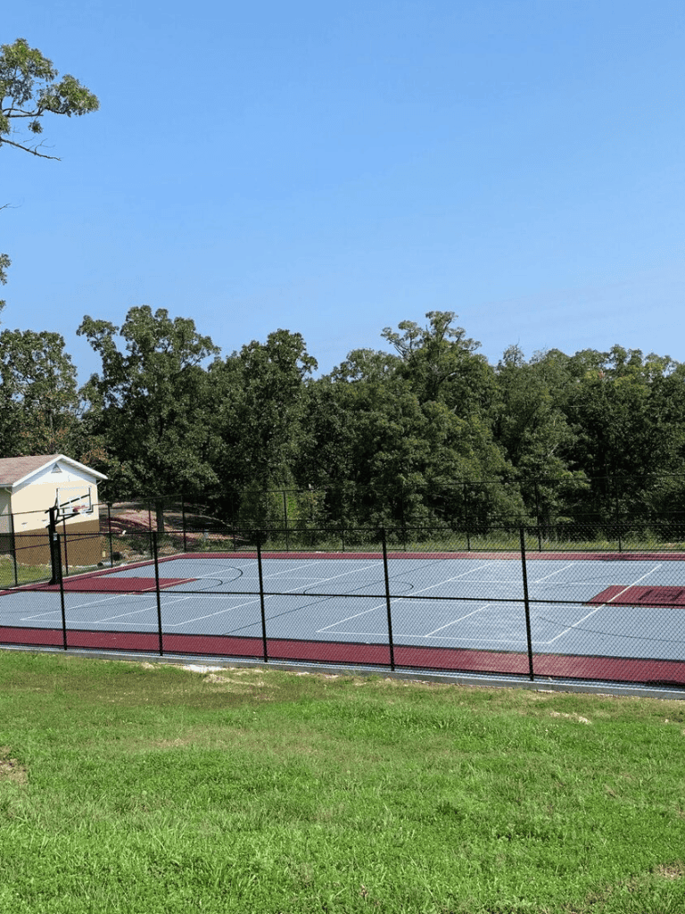 Basketball court at QuestForDirections community park, outdoor sports facility, tennis court, playground, athletic amenities, recreational area.