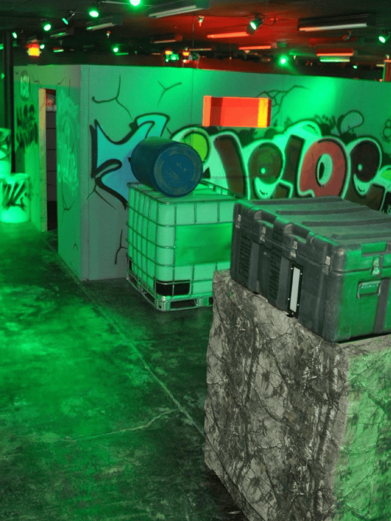 Barrel on stacked crates at laser tag arena with graffiti wall.