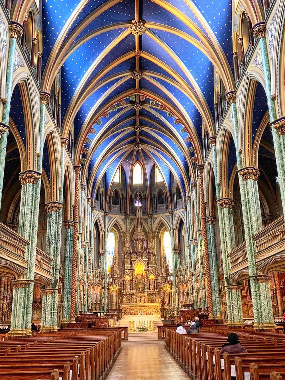 Magnificent Gothic Revival church interior with vibrant blue vaulted ceilings and ornate architectural details.