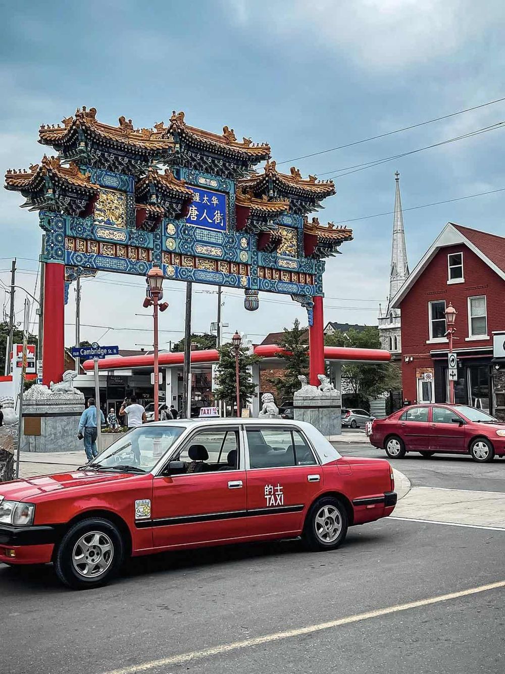 Colorful Chinatown gate in Boston with a red taxi nearby.