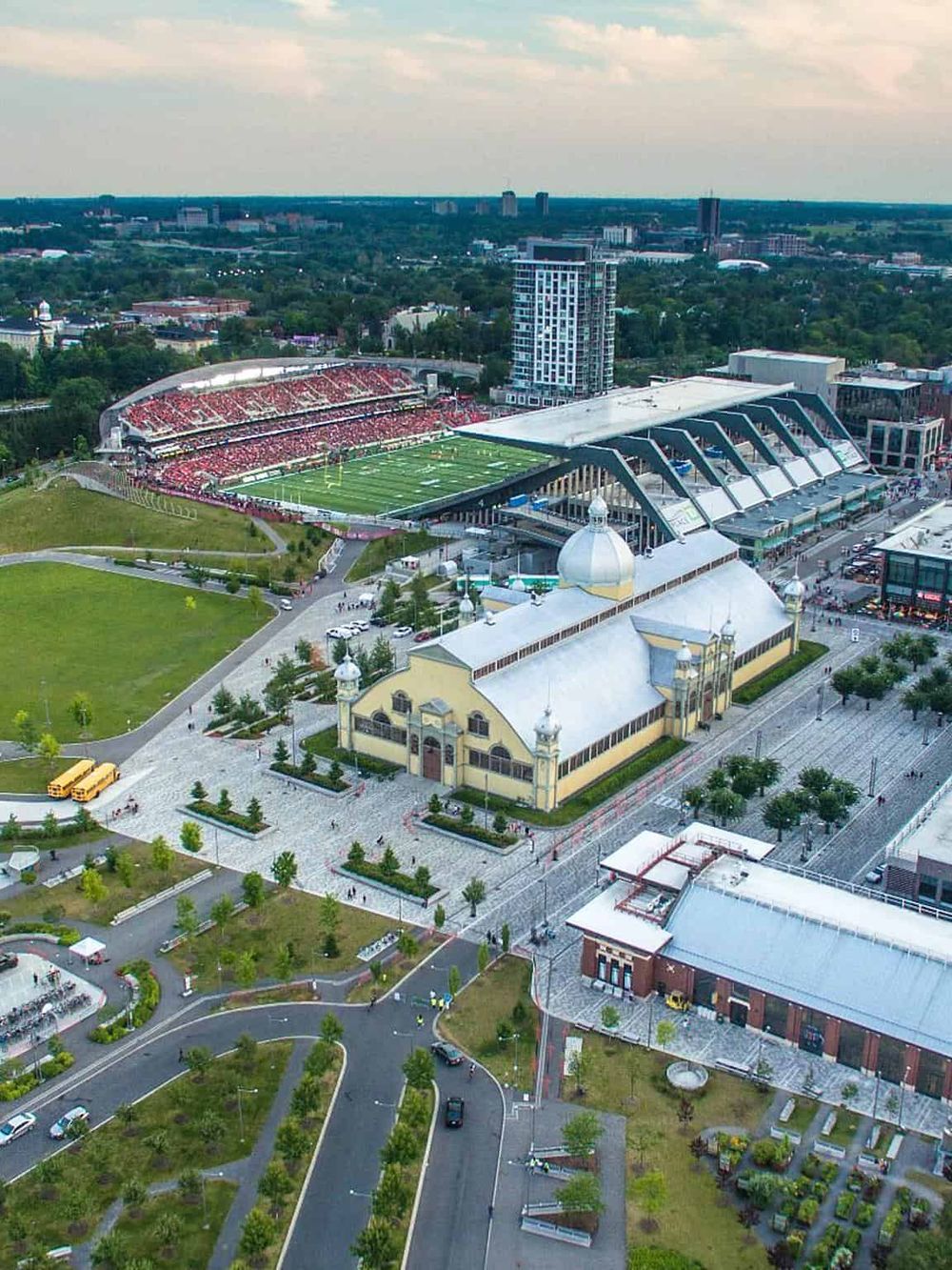 Modern stadium and historic building near downtown with city skyline in background.