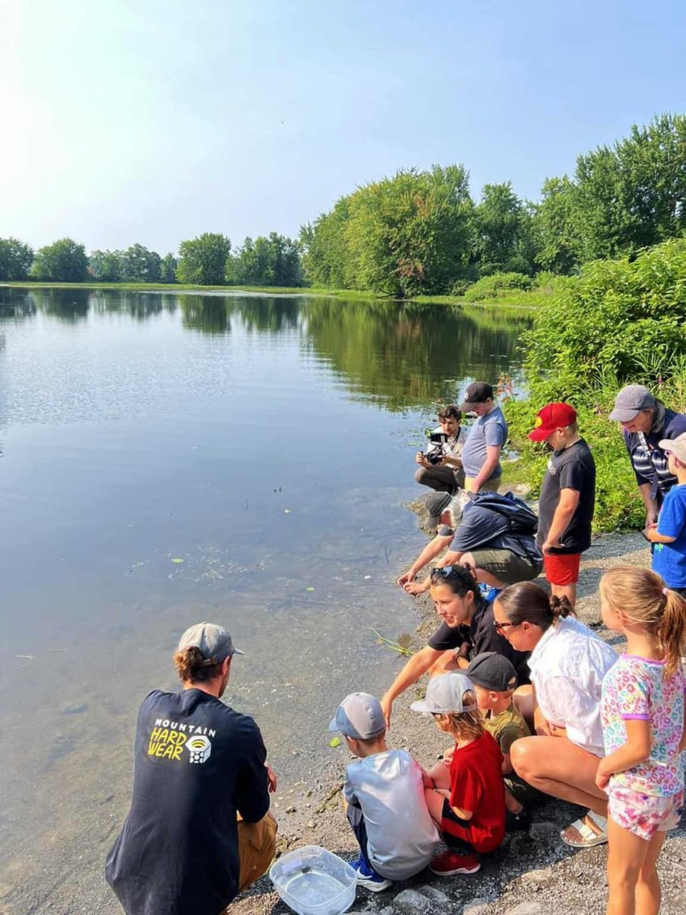 Kids and adults engaging in outdoor nature activities by a peaceful lake, perfect for family recreation and environmental exploration.