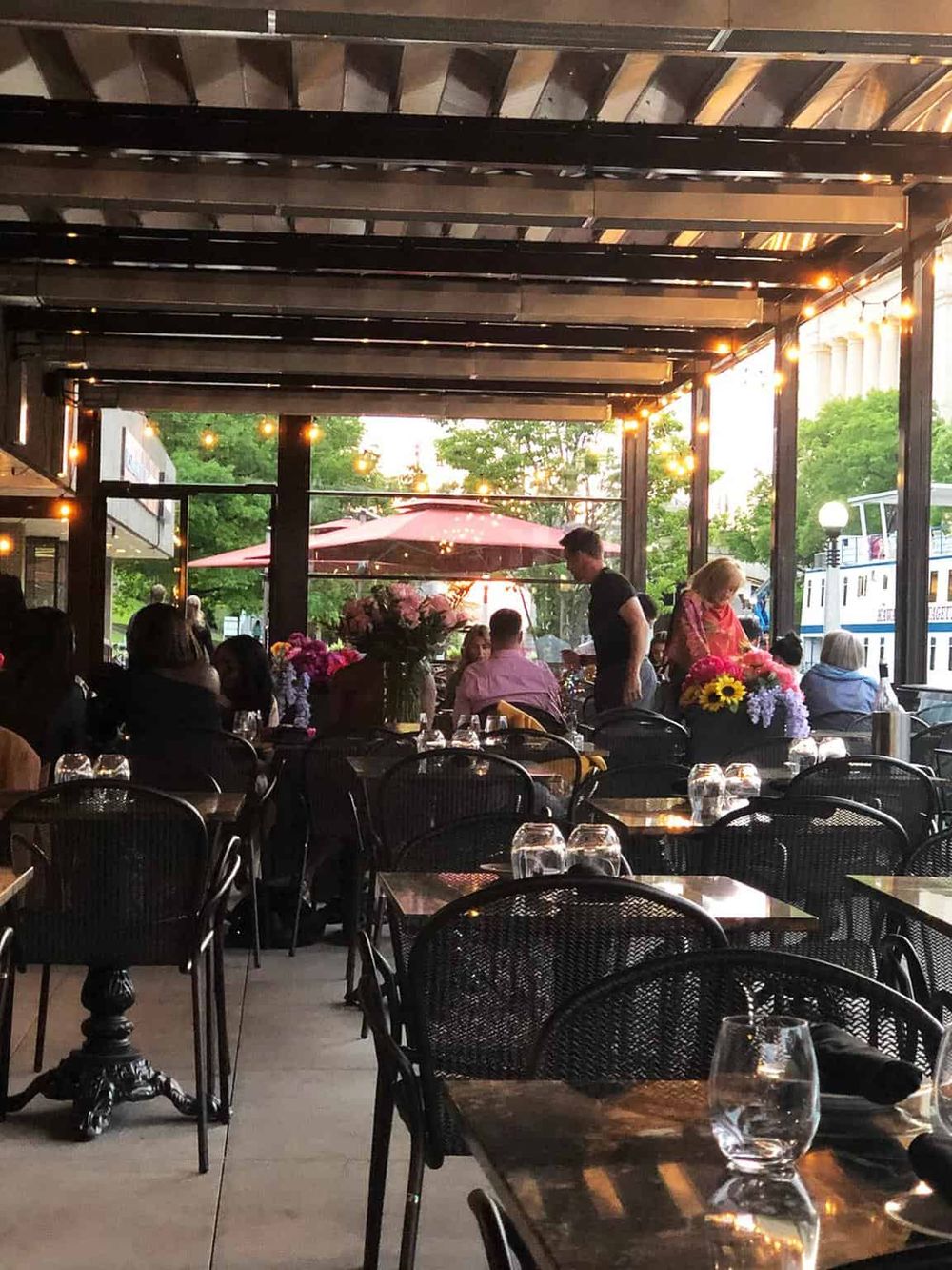 Elegant outdoor dining area at QuestForDirections restaurant with string lights and floral centerpieces.