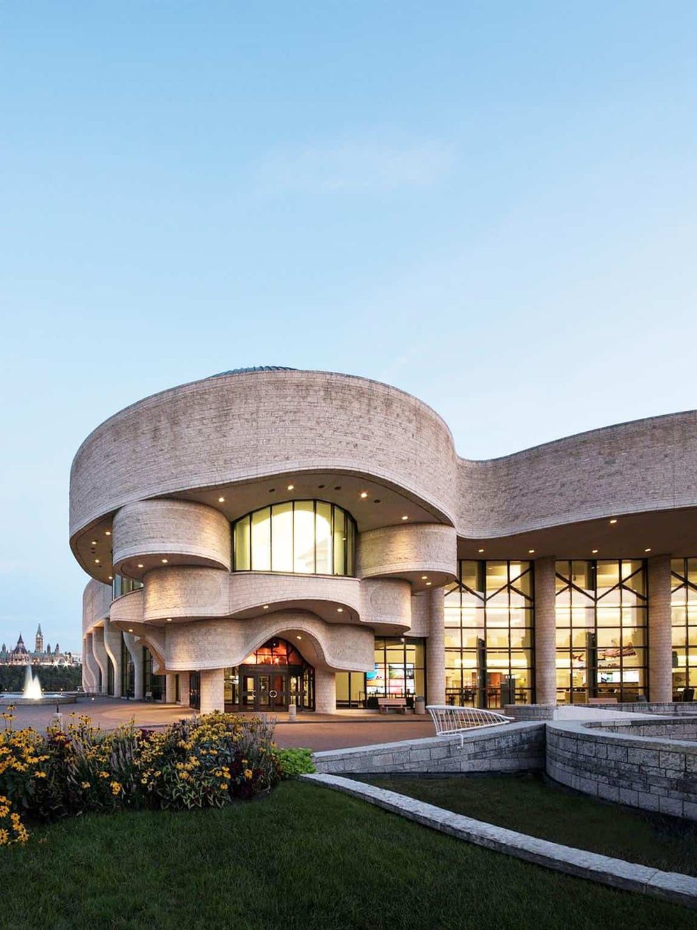 Contemporary museum with unique curvy architecture, large glass windows, and landscaped surroundings.