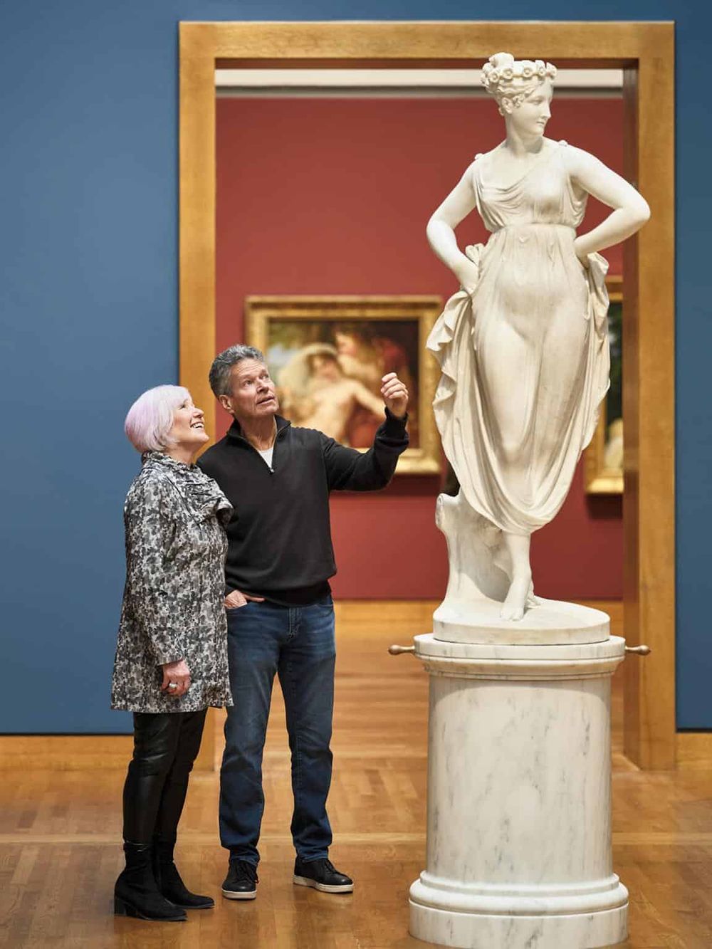 Elegant marble statue of a woman in a museum exhibit, visitors admiring artwork, art gallery, classical sculpture, art appreciation, cultural experience.