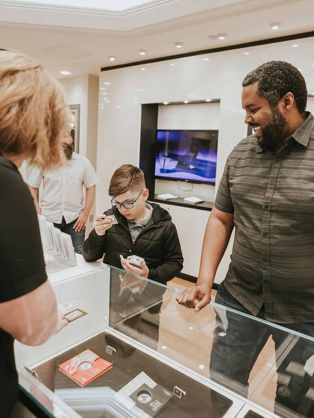 A diverse group of people browsing jewelry at a store counter, engaging in shopping and social interaction.