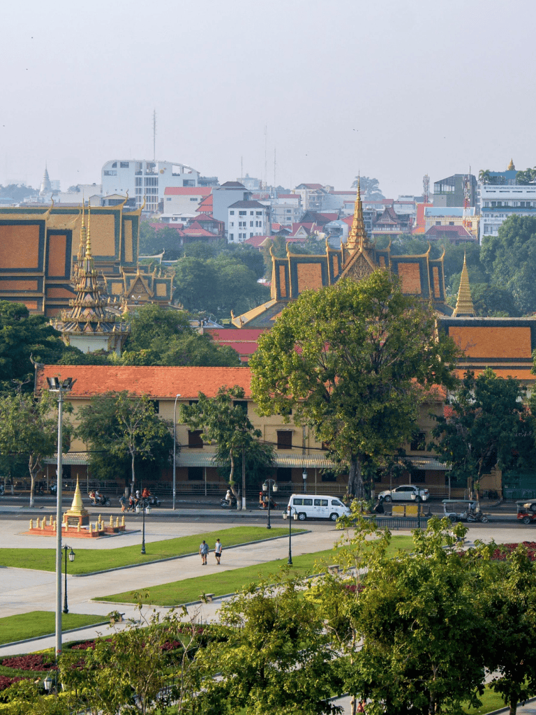 Historic Thai temple with ornate golden rooftops and lush surroundings in Bangkok.