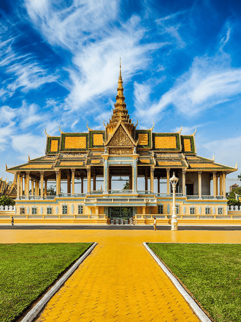 Traditional Cambodian temple with ornate golden roof and intricate architecture under bright blue sky.