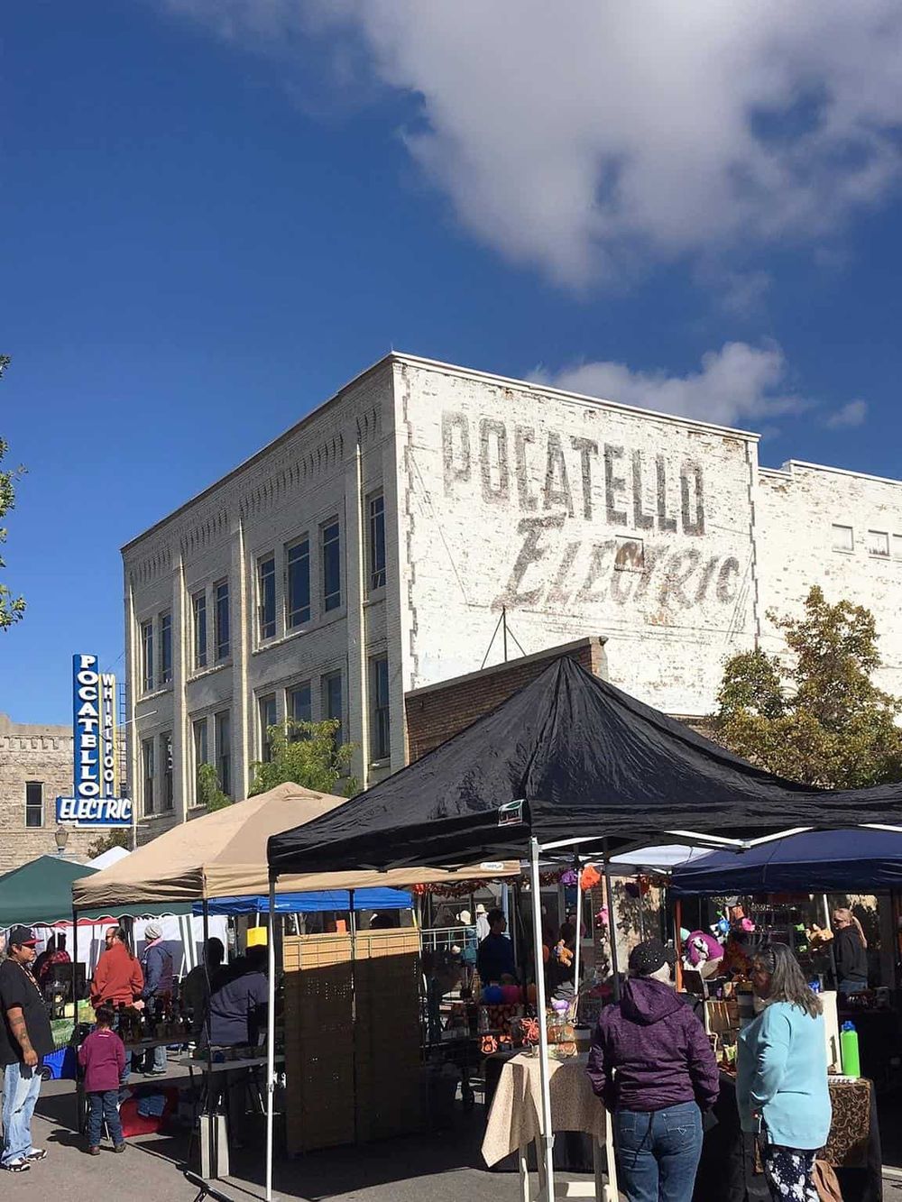 Vibrant outdoor market scene in front of historic Piccadilly building with tents and shoppers.