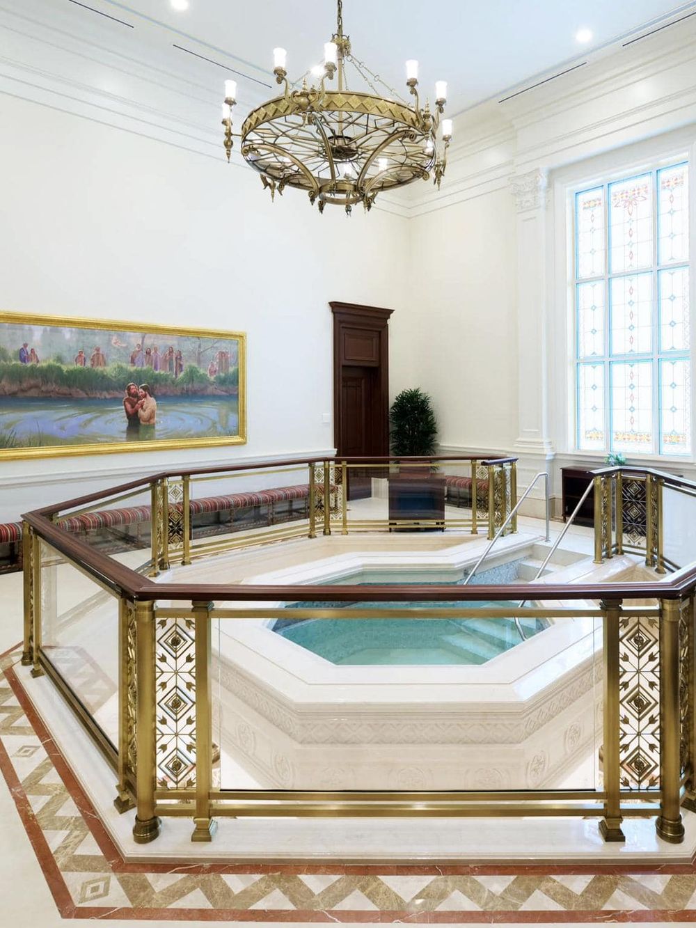 Luxurious indoor pool area with ornate gold railing and chandelier, elegant interior, and large stained glass windows.