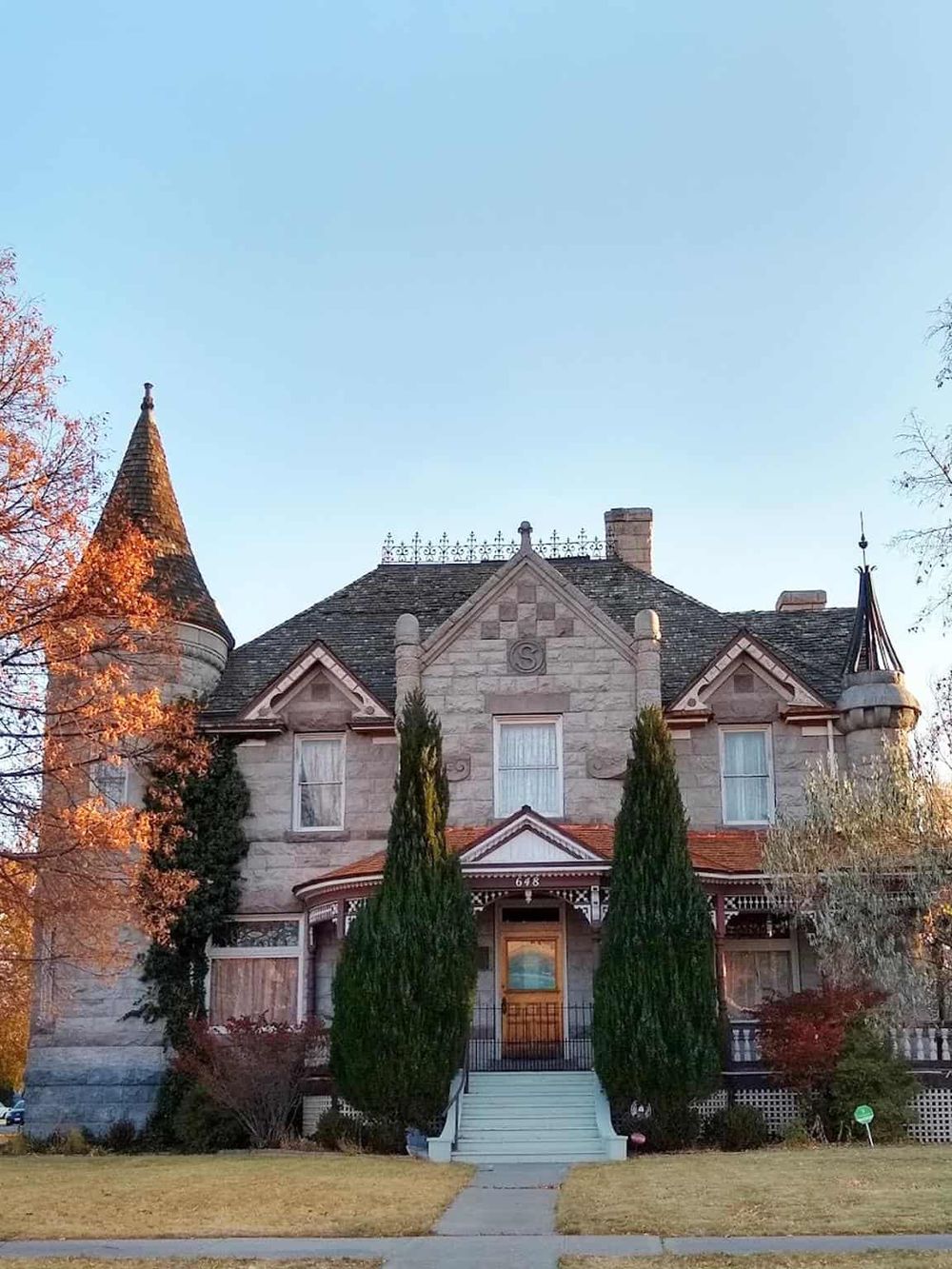 Victorian-style house with turrets, ornate woodwork, and lush landscaping in a scenic neighborhood.