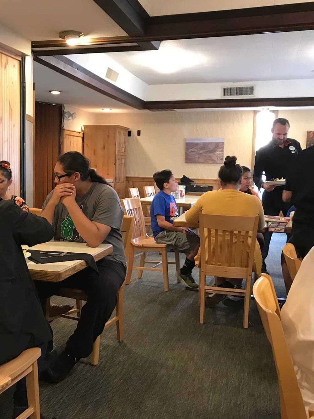 Cozy family restaurant interior with children dining and staff serving, perfect for dining out and food delivery.