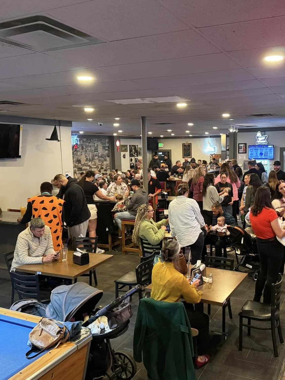 Busy indoor restaurant crowded with diverse patrons enjoying meals and socializing.