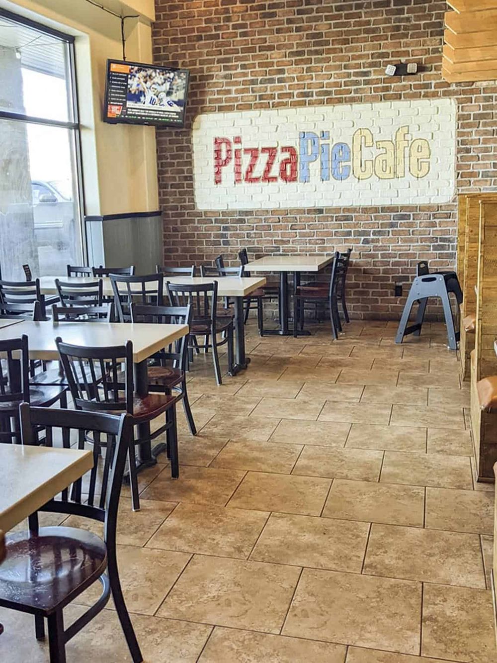 Cozy pizza café interior with brick walls, wooden floors, and tables for dine-in, perfect for pizza lovers.