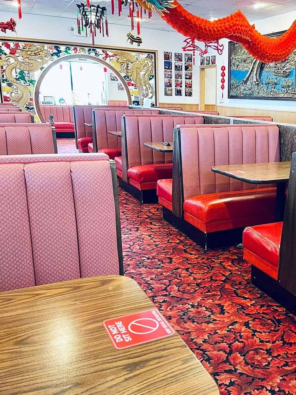 Vibrant Chinese restaurant interior with red booths, dragon decor, and cultural artwork for dining experience.