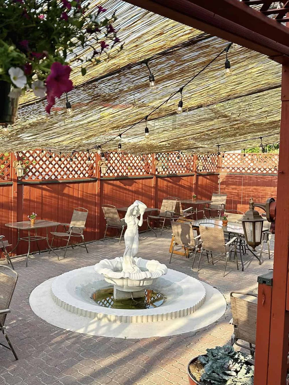 Cozy outdoor patio with fountain, string lights, and garden furniture for relaxing dining experience.